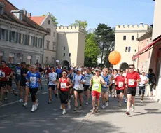 Un groupe de coureurs en vêtements de sport courant dans une rue de ville, certains tenant un ballon orange.