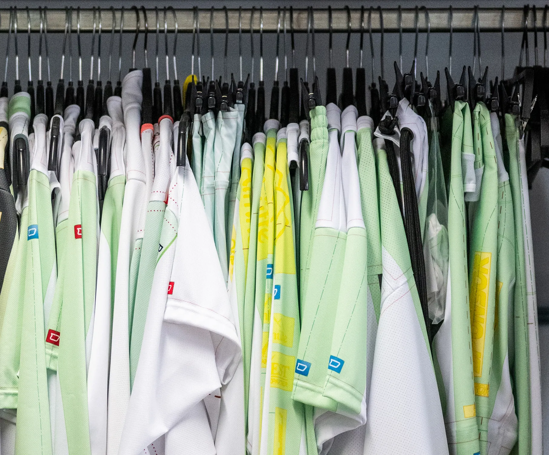 Une sélection de vêtements de sport personnalisés de différentes couleurs suspendus à des cintres.