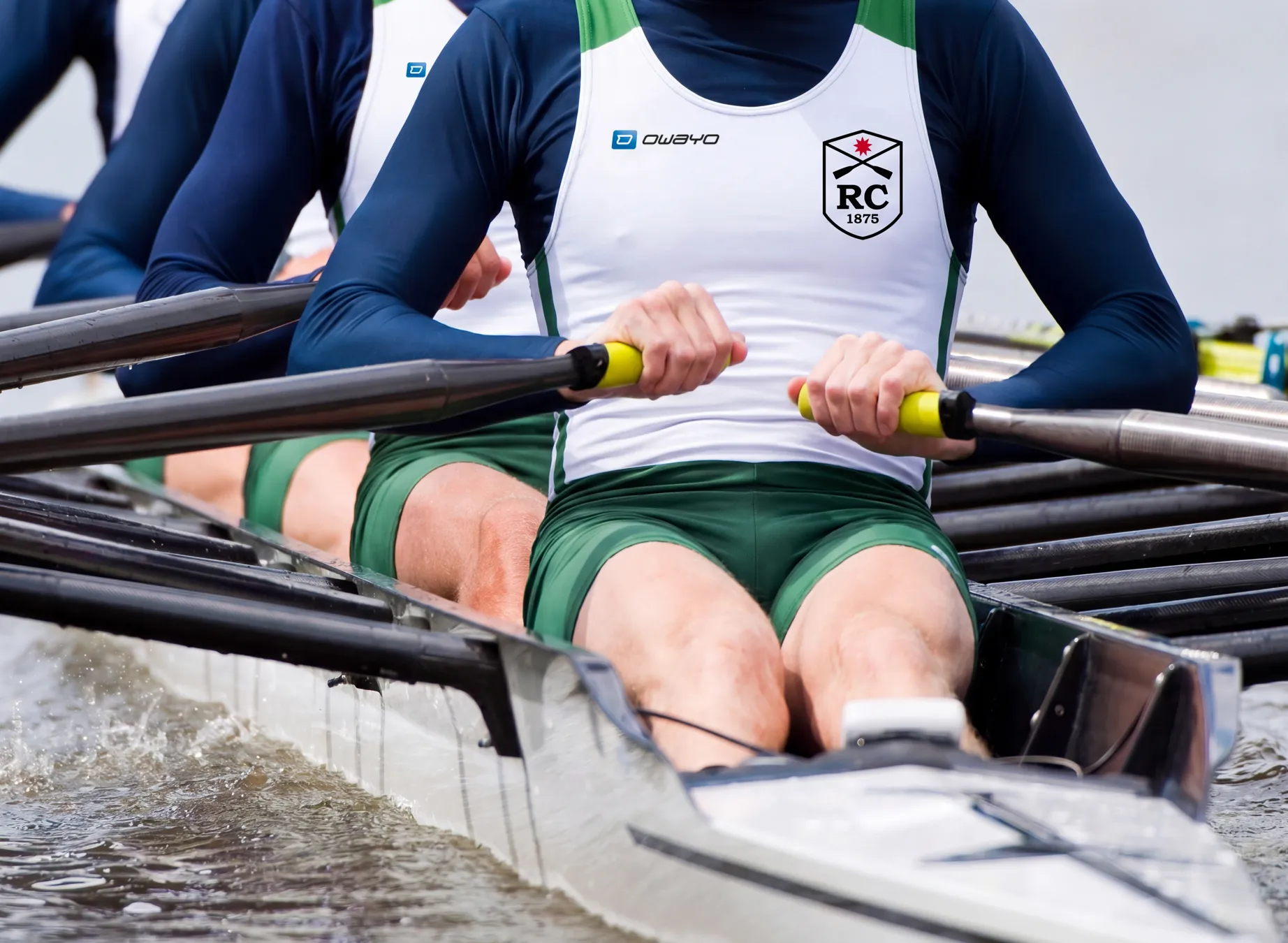 Un groupe de rameurs en vêtements de sport personnalisés, rament activement dans un bateau.